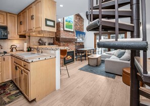 A modern kitchen with wooden cabinets, a built-in island, and a fireplace. - Wall Street 307, 1BD + Loft Condo in Vail Village (Vail)