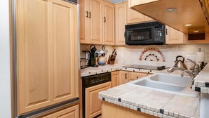 Una cocina con armarios de madera, microondas, lavavajillas y salpicadero de azulejos.
