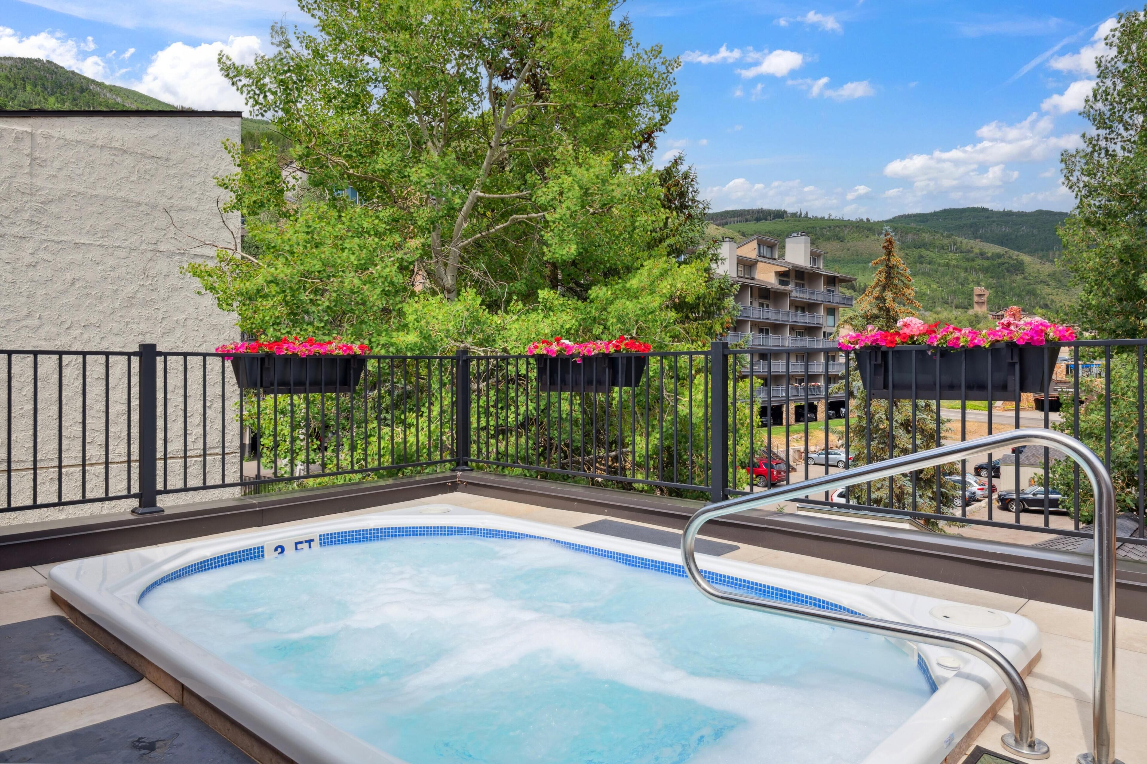 Un jacuzzi con vistas a una montaña y un edificio al fondo.