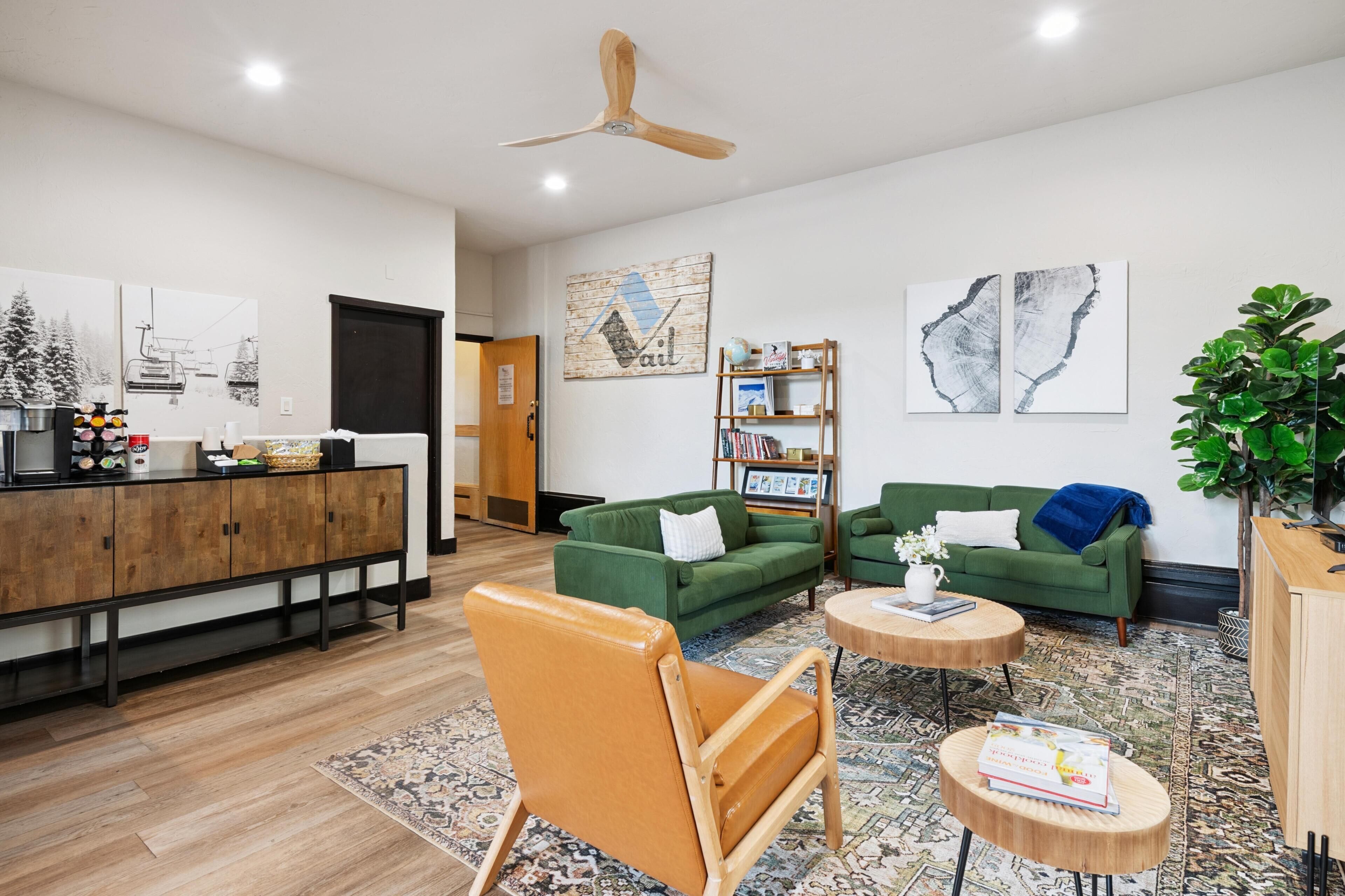 Una sala de estar moderna con un aparador de madera, sofás verdes, una silla de madera y una mesa de centro.