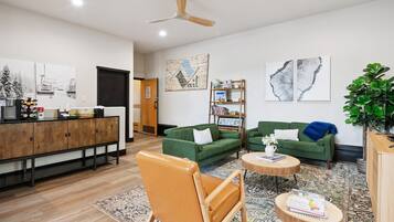 Una sala de estar moderna con un aparador de madera, sofás verdes, una silla de madera y una mesa de centro.