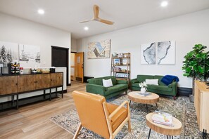 Een moderne woonkamer met een houten kast, groene banken, een houten stoel en een salontafel.