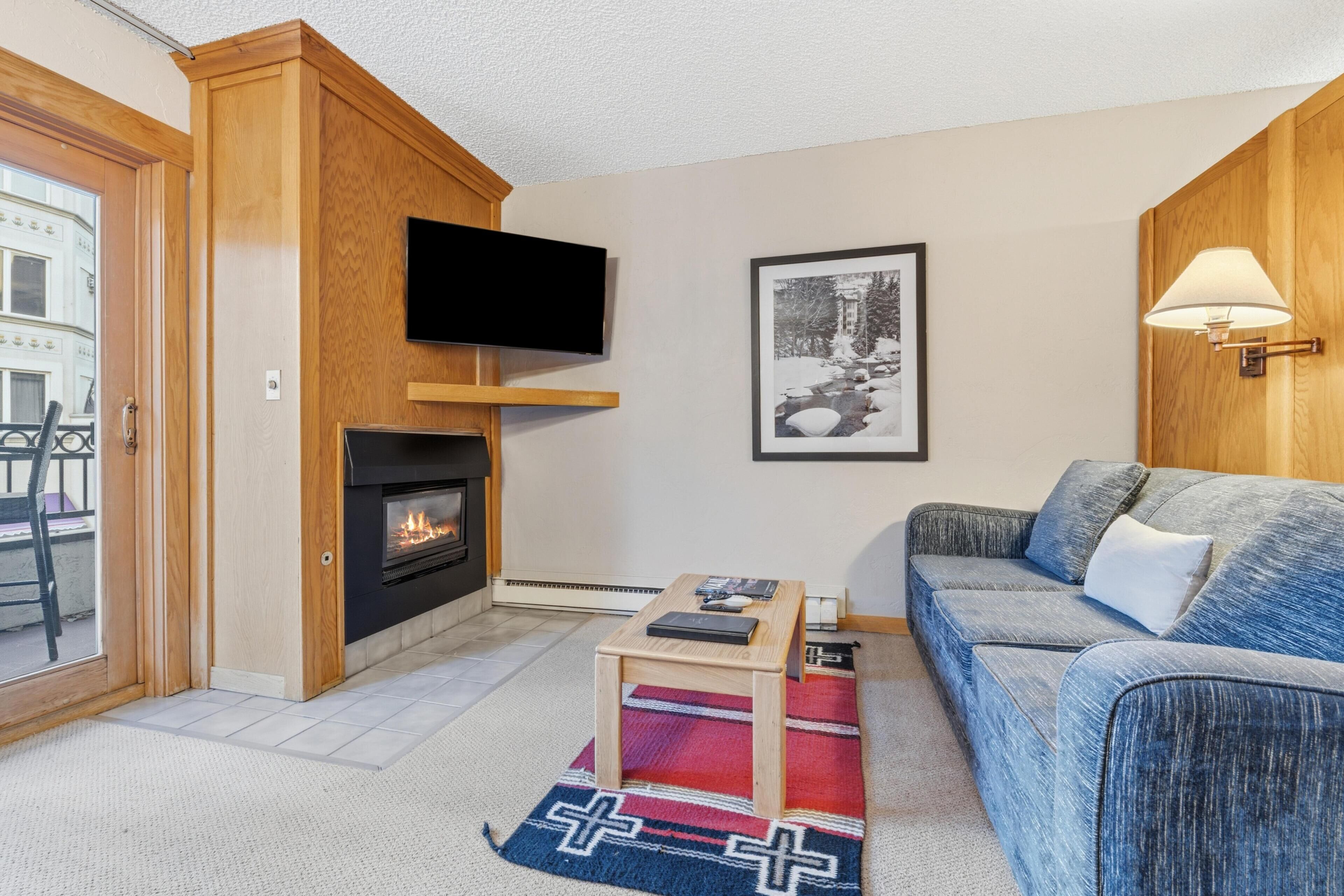 A living room with a fireplace, a television mounted on the wall, a sofa, and a coffee table.