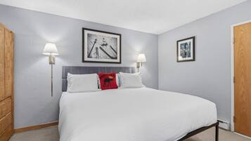 Un dormitorio con una cama, dos lámparas de pared y dos cuadros en la pared.