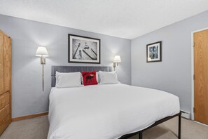 Een slaapkamer met een bed, twee wandlampen en twee ingelijste foto's aan de muur.