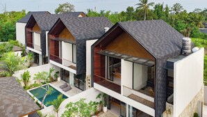 A modern multi-story building with balconies, a swimming pool, and lush greenery. - Bintang Villas Ubud (Ubud)