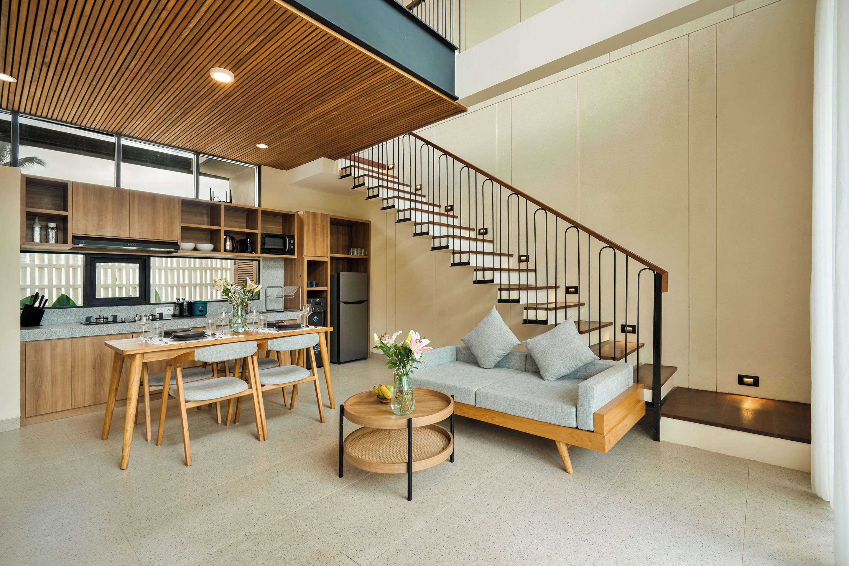 A modern interior with a dining area, kitchen, and a staircase.