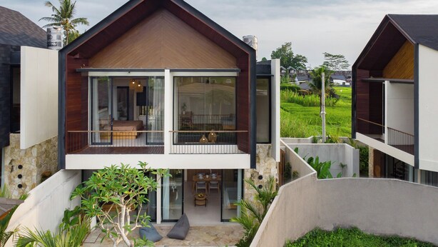 Ein modernes, zweistöckiges Haus mit Balkon, Schwimmbad und üppiger Bepflanzung.