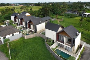 Un moderno edificio residencial de varios pisos con piscina, rodeado de exuberante vegetación y campos.