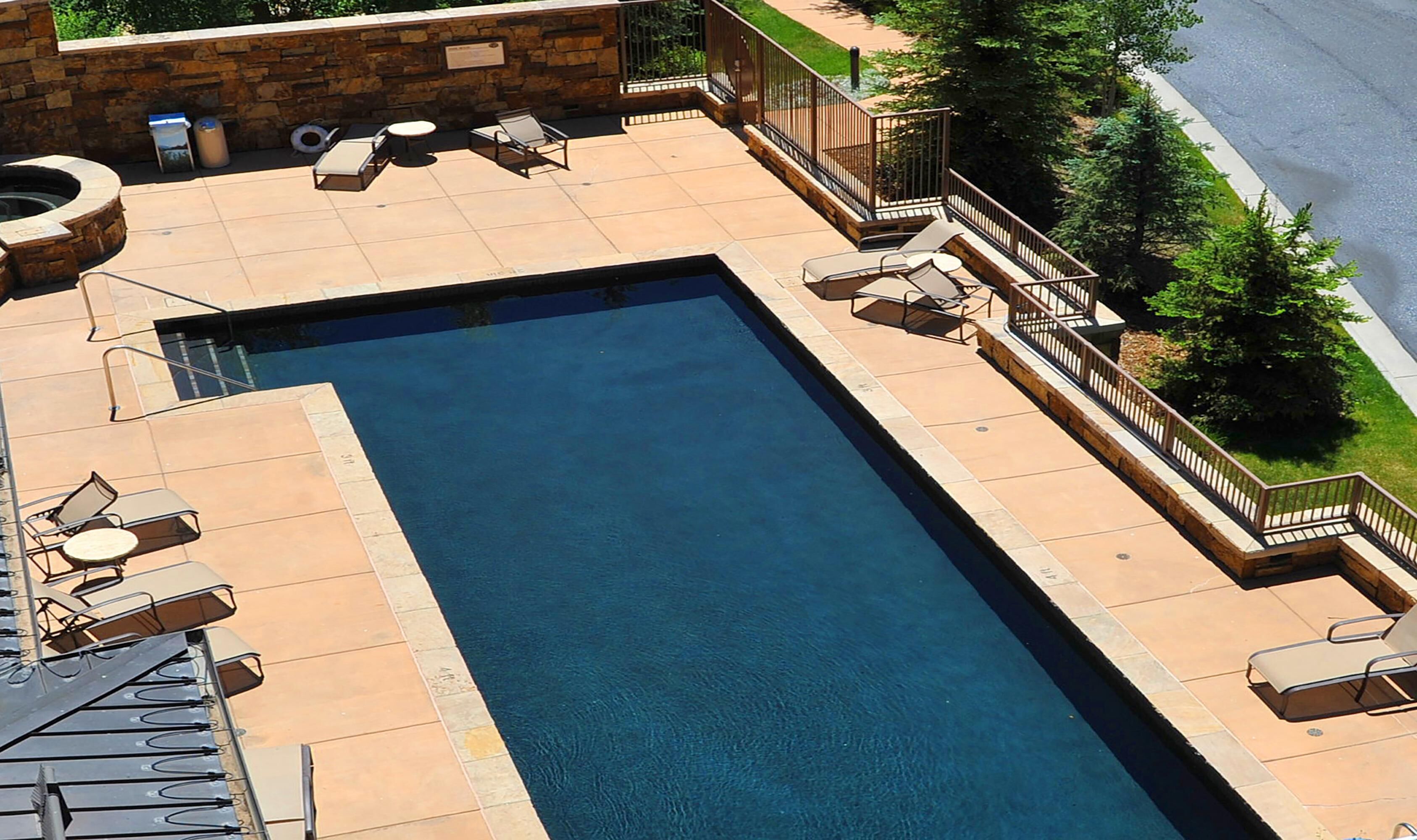 A rectangular pool with lounge chairs and a stone wall.