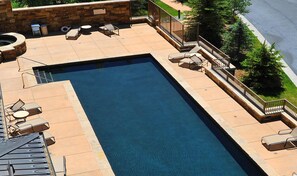 Ein rechteckiger Pool mit Liegestühlen und einer Steinmauer.