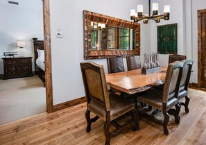 Ein Essbereich mit Holztisch, Ledersesseln, einem großen Spiegel und einer Chandelüstere.