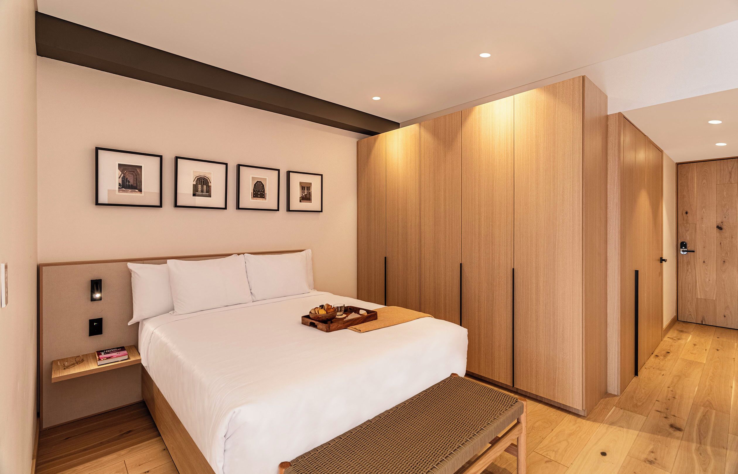 Ein modernes Schlafzimmer mit einem großen Bett, einem Holzschrank und gerahmten Bildern an der Wand.