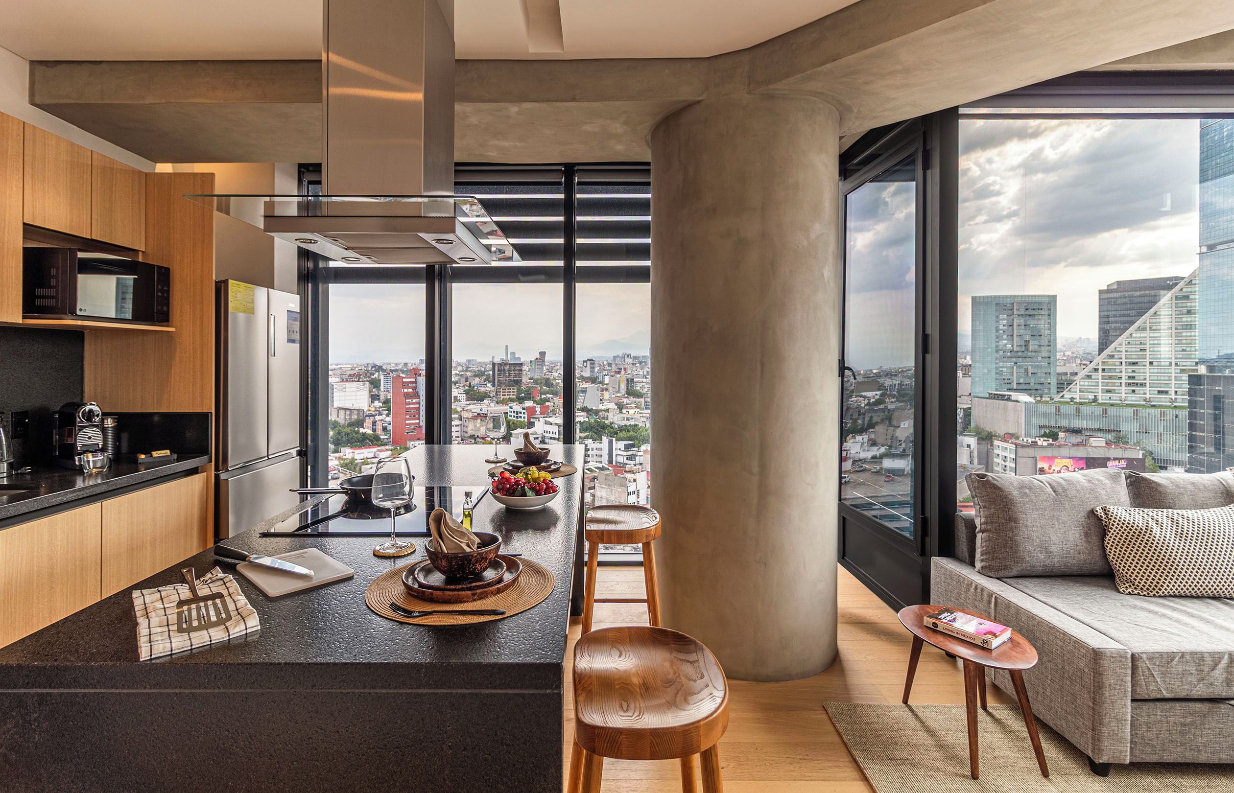 Eine moderne Küche mit Stadtblick, ein Essbereich mit Sofa und Tisch sowie ein großes Fenster.