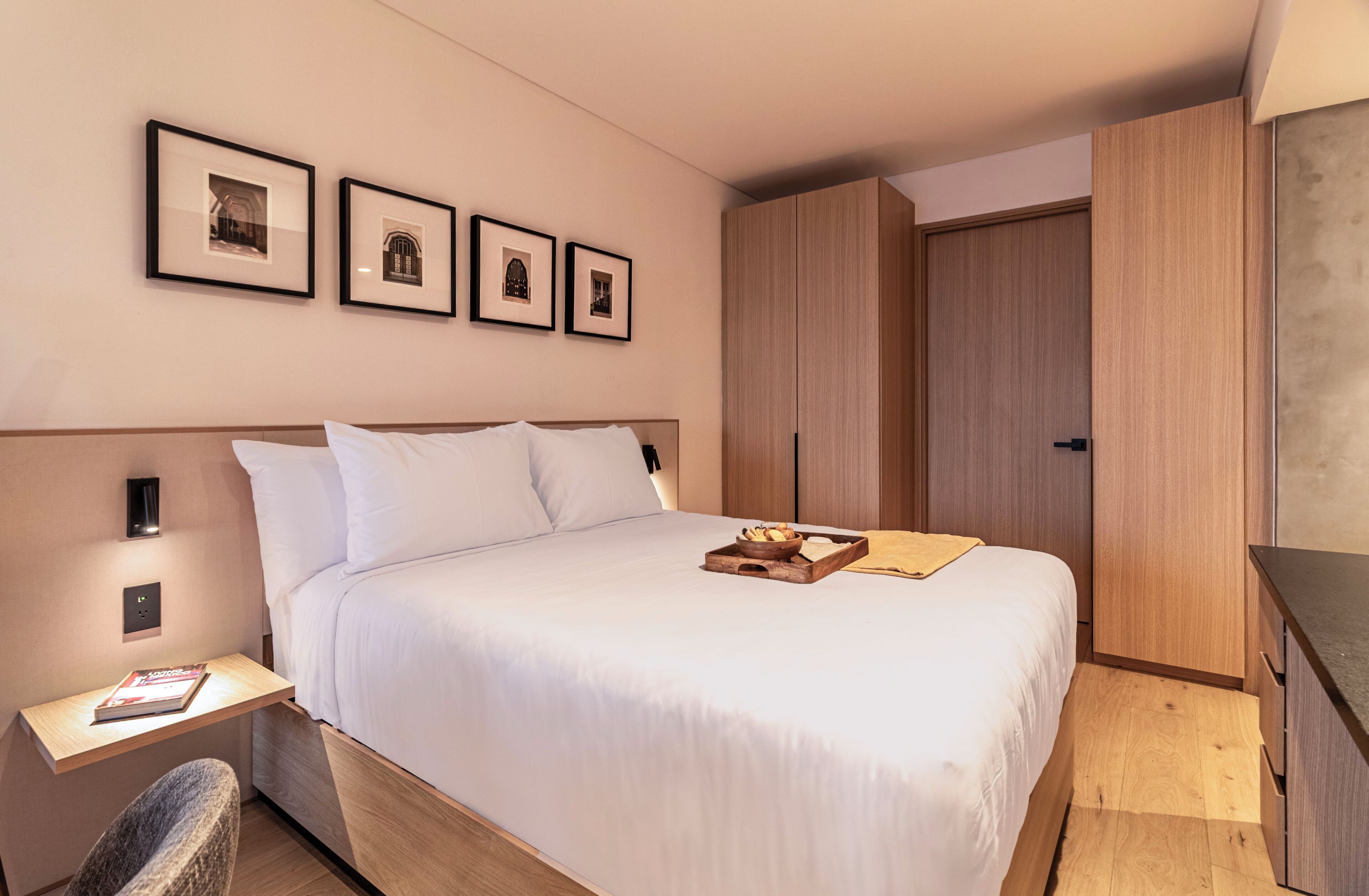 Una camera d'albergo con un letto, un comodino, un'opera d'arte appesa al muro e un armadio.