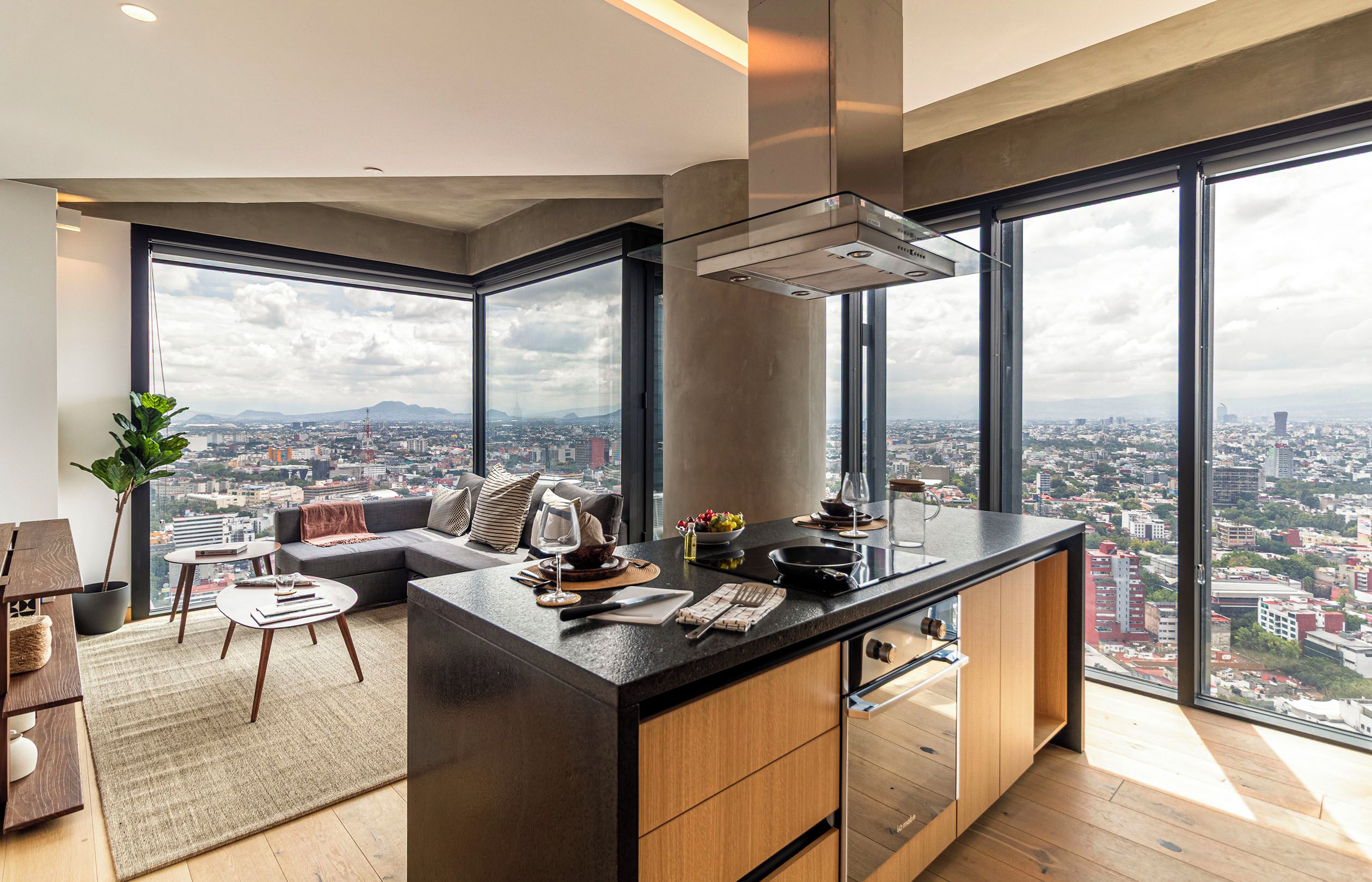 A modern kitchen with a large island, a dining area with a sofa, and a view of the city.