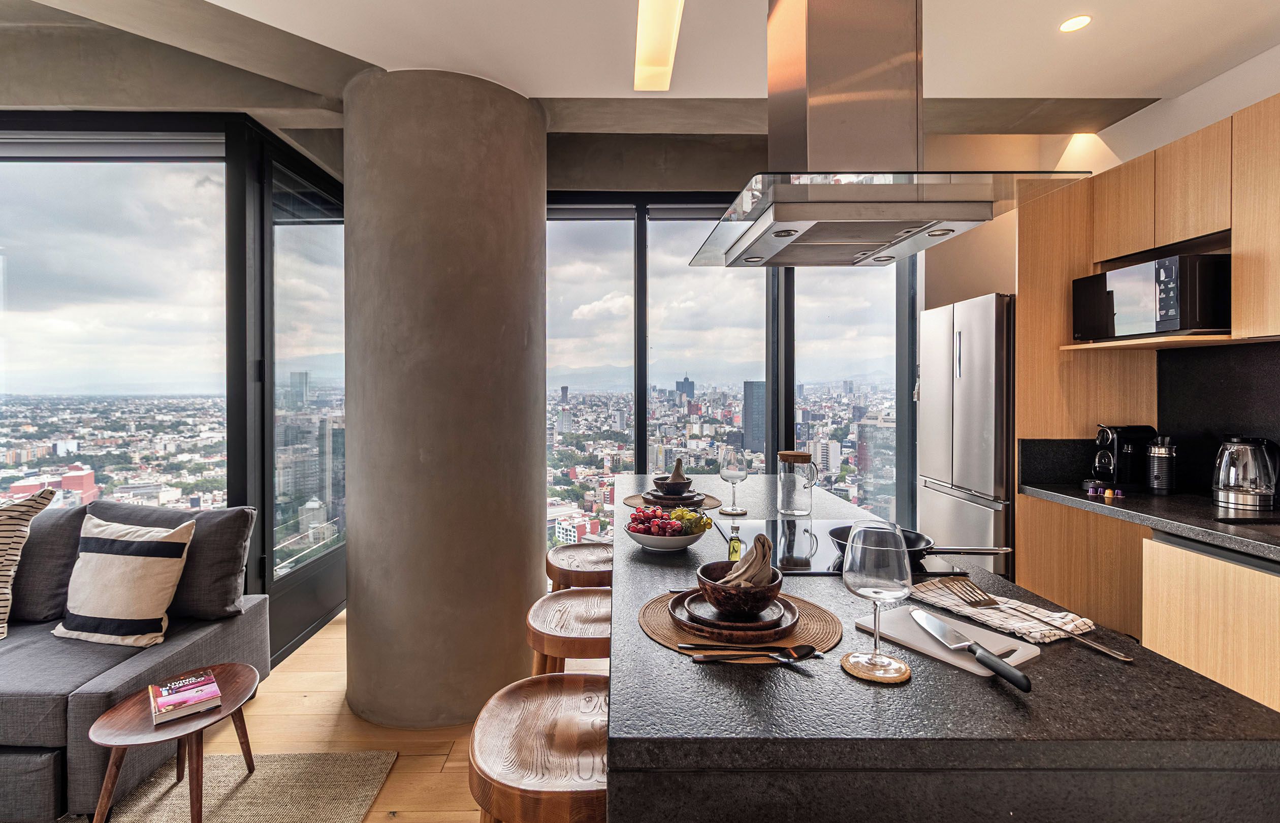 Cozinha moderna com vista para a cidade, área de refeições com mesa redonda e sofá com almofadas.