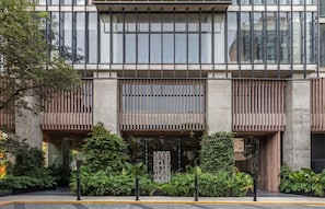 Un edificio moderno con amplios ventanales, fachada de madera y un jardín bien cuidado.