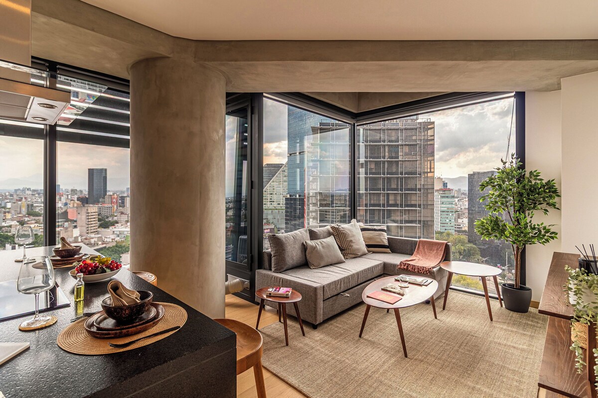 Una sala de estar moderna con un sofá, una mesa de centro y un comedor con una mesa de vidrio y sillas.