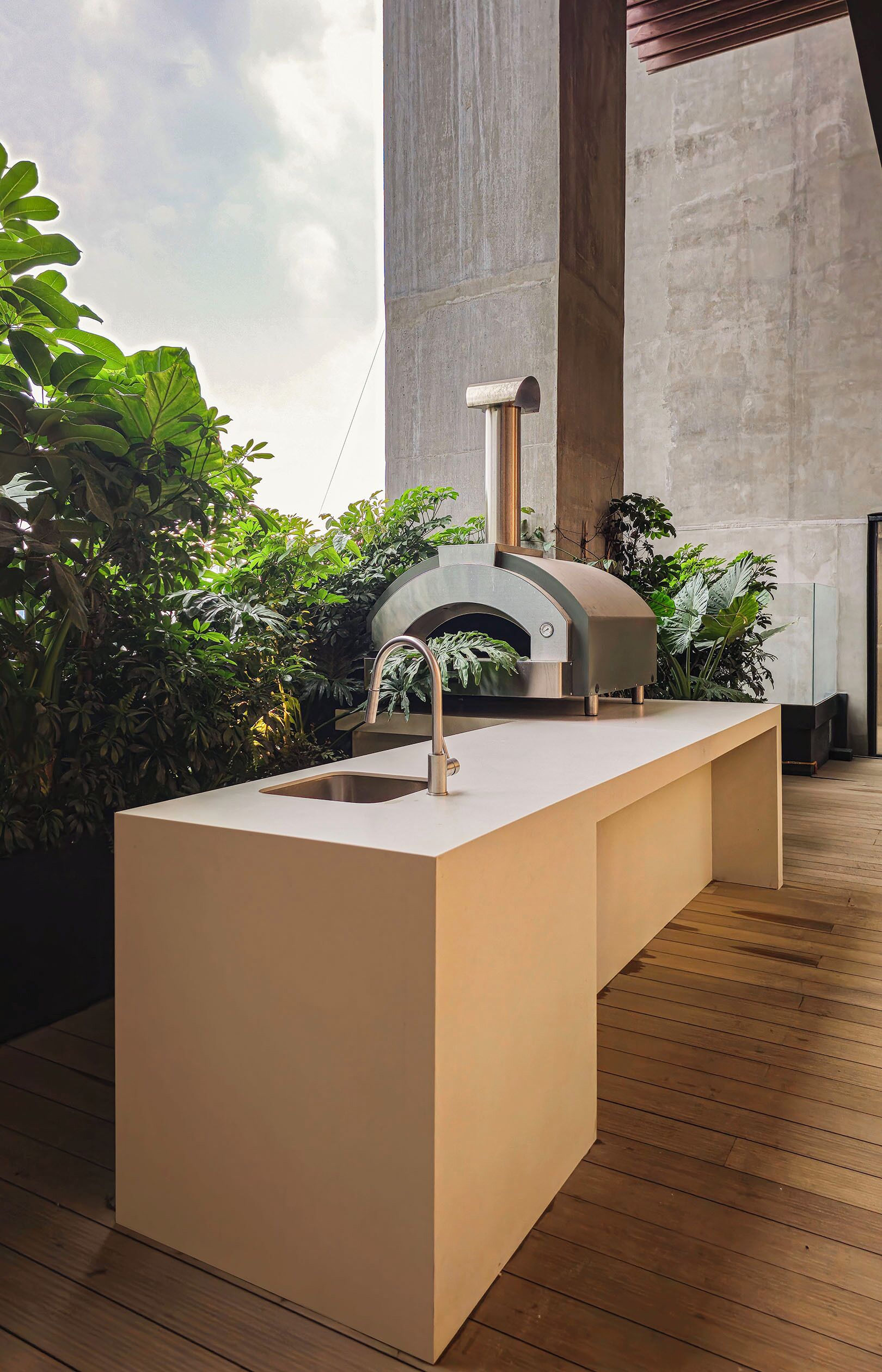 Una cocina moderna con horno y pileta integrados, rodeada de abundante vegetación.
