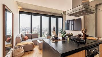 A modern kitchen with a large island, a built-in oven, and a city view through large windows.