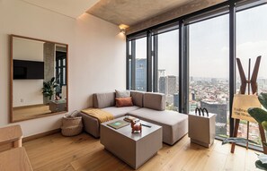 Een moderne woonkamer met een groot raam, een bank, een salontafel en een televisie.