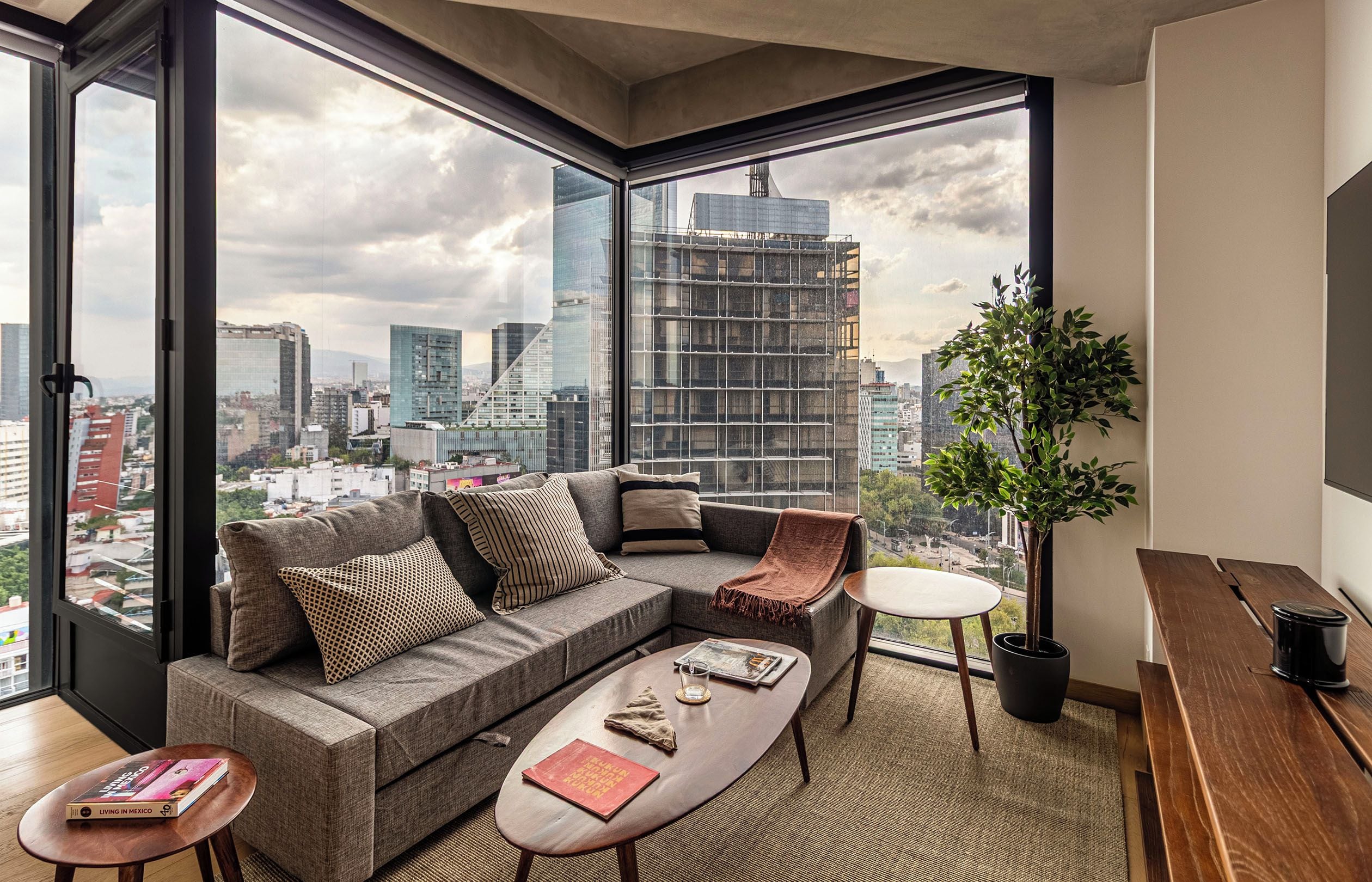 A modern living room with a large window, a sofa, a coffee table, and a small side table.