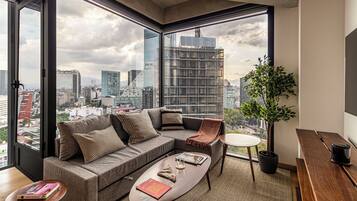 A modern living room with a large window, a sofa, a coffee table, and a small side table.
