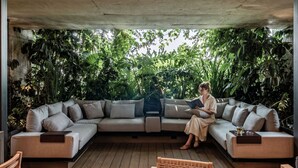 Un espace de vie extérieur moderne comprenant un canapé, des fauteuils et une table.