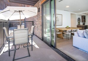 A modern interior with a dining area, a sofa, and a kitchen visible through glass doors. - Frontgate 213, 4 BD Condo in Avon With Amenities (Avon)