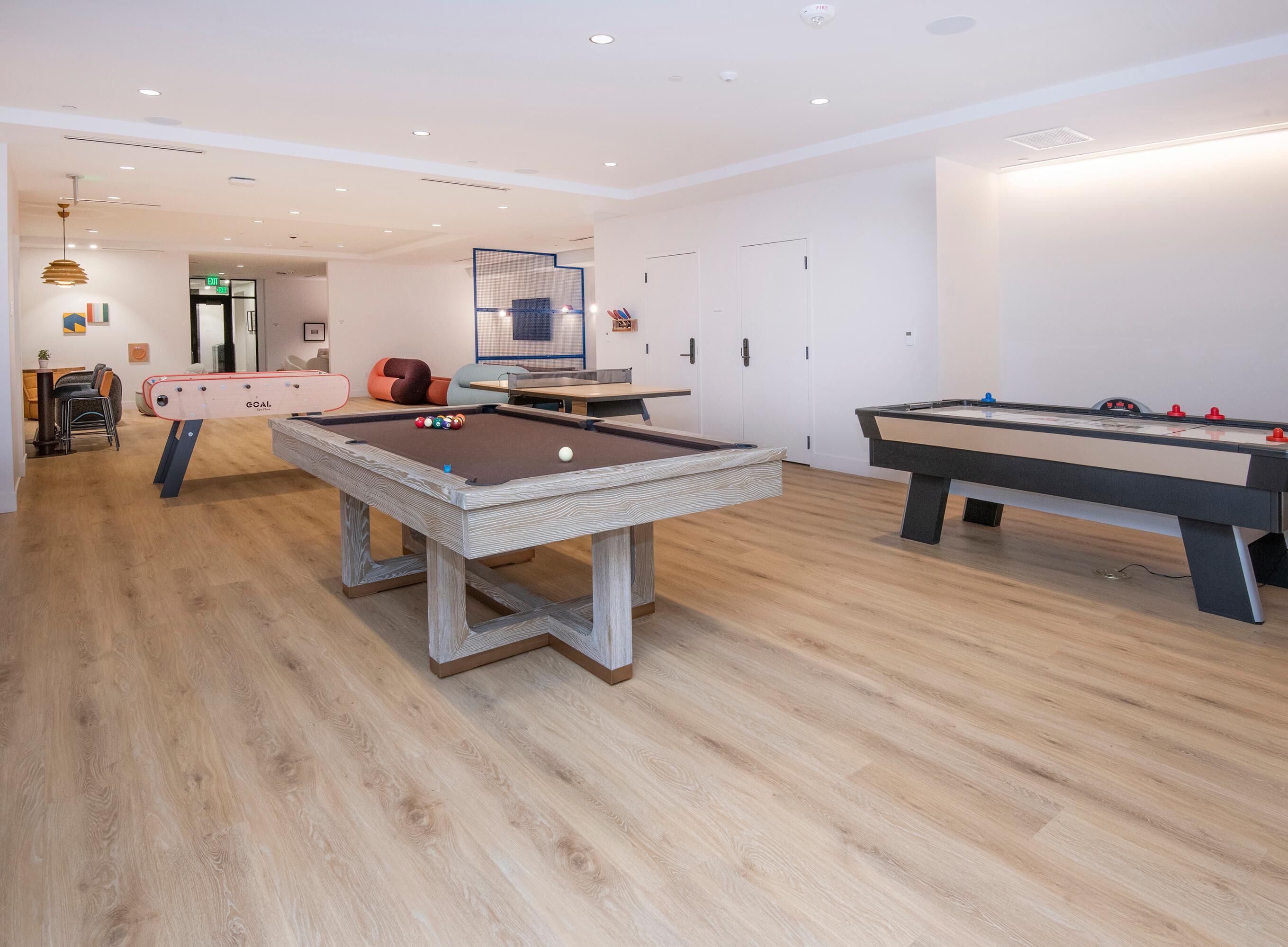 A pool table, another pool table, and a dining area with chairs and a table.