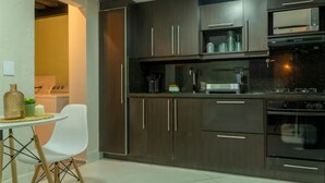 Une cuisine moderne avec des meubles de couleur sombre, un four à micro-ondes et une cuisinière.