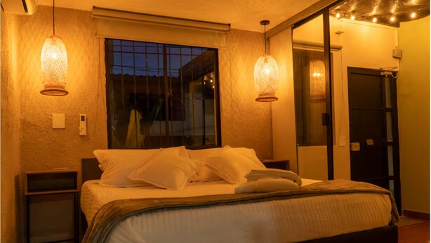 Une chambre à coucher avec un lit, des tables de chevet, une fenêtre et un miroir.
