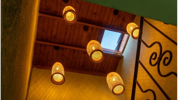 Een kamer met houten plafond, een raam en een wandlamp.