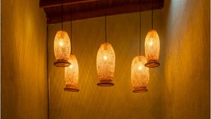 Een muur met drie hanglampen en een metalen poort met decoratieve patronen.