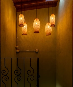 A wall with three hanging lamps and a metal gate with decorative patterns. - Modern Suite with Private Balcony • A/C • WiFi (Medellín)