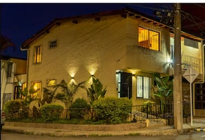 A two-story building with a balcony, a gated entrance, and a well-lit facade. - Modern Suite with Private Balcony • A/C • WiFi (Medellín)