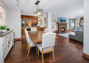 A modern kitchen with wooden cabinets, a dining table with chairs, a fireplace, and a living area with a sofa. - Ascent 301, 3BD Condo in Avon With Amenities (Avon)
