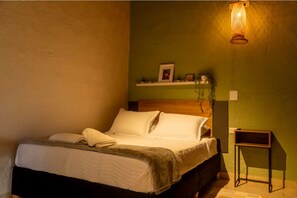 A neatly made bed with a wooden headboard, a bedside table, and a wall-mounted shelf with decorative items. - Modern Private Suite Terrace + Self Check-in (Medellín)