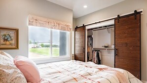 Un dormitorio con una cama grande, un armario con puerta corredera y una ventana con cortinas.