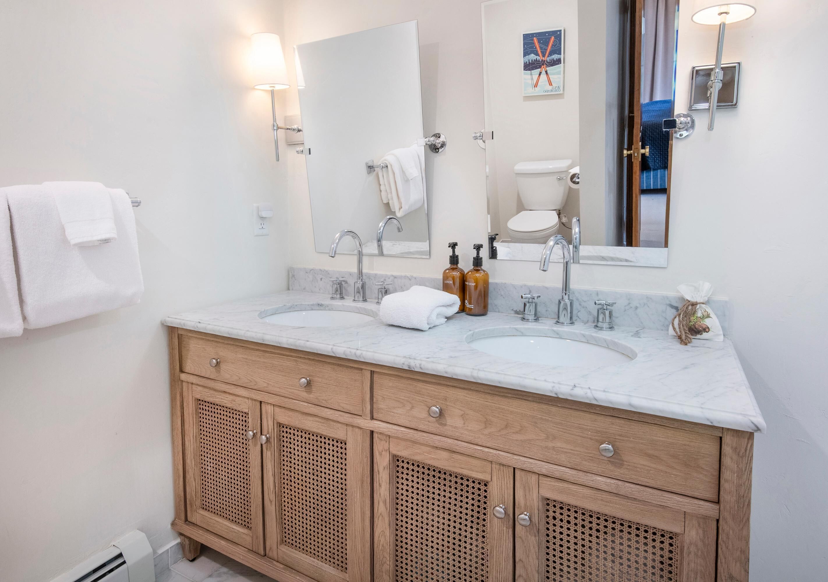 A bathroom with two sinks, wooden cabinets, a large mirror, and a towel rack.
