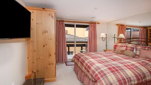 A bedroom with a large bed, wooden wardrobe, and a balcony with curtains. - Creekside 3, 2BD + Loft in Heart of Vail Village (Vail)
