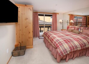 A bedroom with a large bed, wooden wardrobe, and a balcony with curtains. - Creekside 3, 2BD + Loft in Heart of Vail Village (Vail)