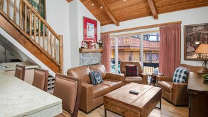 A spacious living area with leather sofas, a wooden coffee table, and a stone fireplace. - Creekside 3, 2BD + Loft in Heart of Vail Village (Vail)