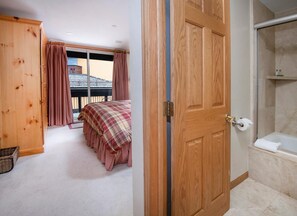 Ein Schlafzimmer mit Bett, Holzschrank und Badezimmer mit Badewanne.
