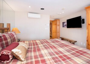 Ein Schlafzimmer mit einem Bett, einem an der Wand montierten Fernseher und einer Klimaanlage.