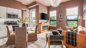 A modern living room with a fireplace, a television, and a dining area. - Free Gated Parking • Music Row Condo • Pool • Rooftop Club Room with Pool Table (Nashville)
