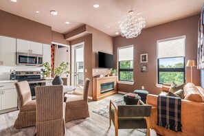 A modern living room with a fireplace, a television, and a dining area. - Free Gated Parking • Music Row Condo • Pool • Rooftop Club Room with Pool Table (Nashville)