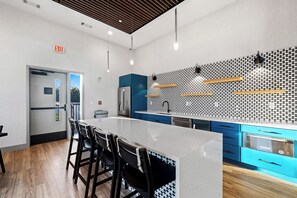 A modern kitchen with a central island, blue cabinets, and a patterned backsplash. - Free Gated Parking • Music Row Condo • Pool • Rooftop Club Room with Pool Table (Nashville)