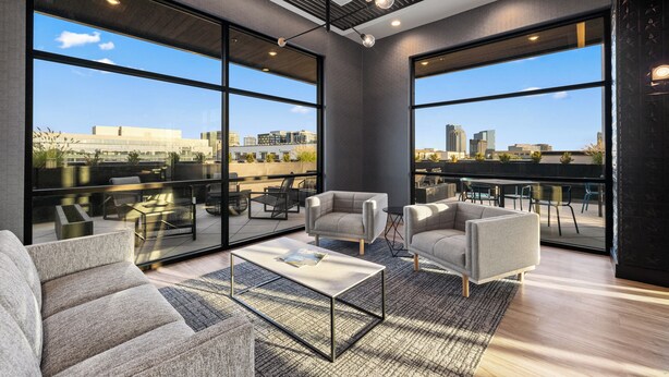 A modern interior with large windows, a sofa, a coffee table, and a city view. - Free Gated Parking • Music Row Condo • Pool • Rooftop Club Room with Pool Table (Nashville)